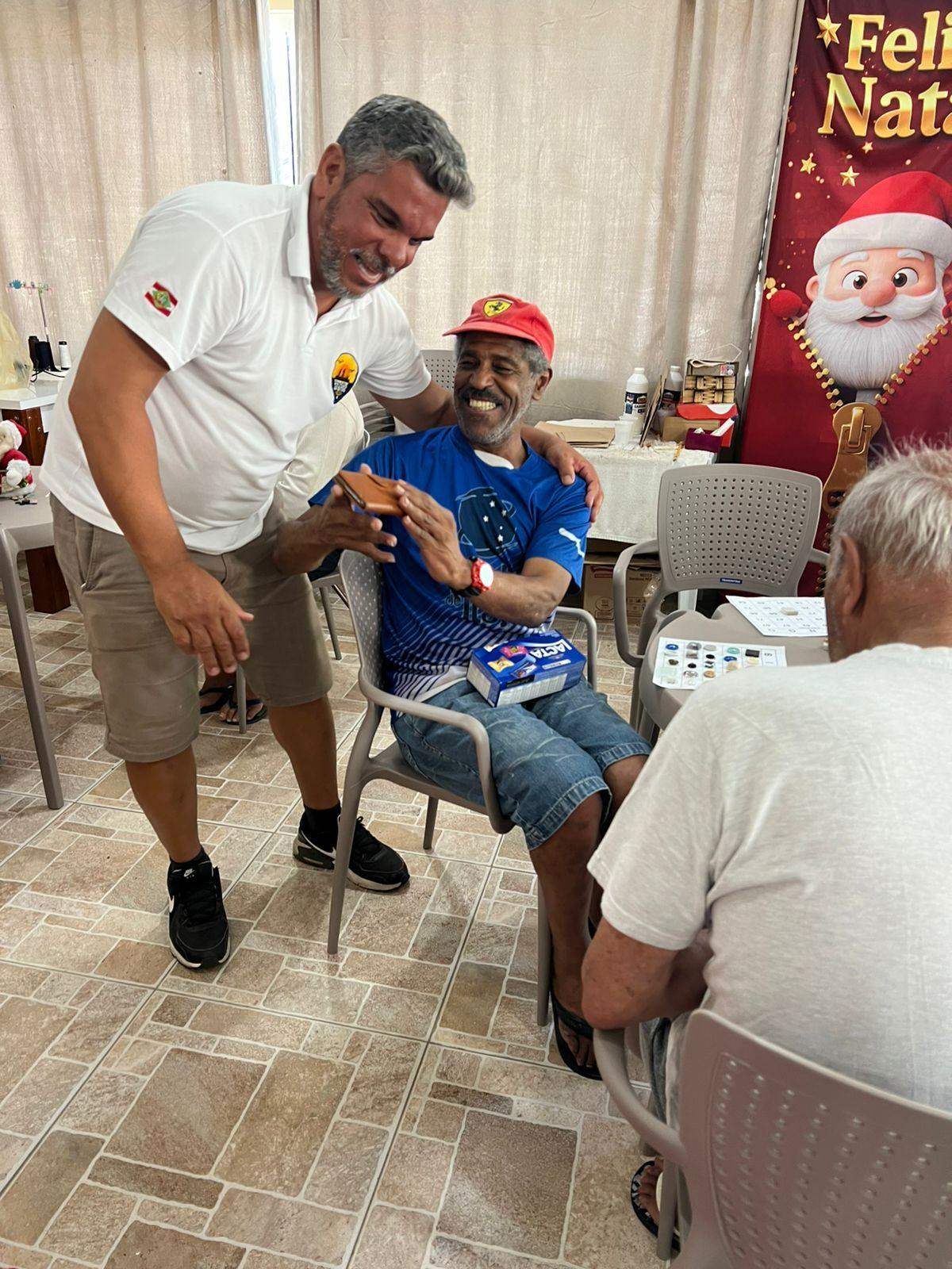 Voluntário conversa e sorri com moradores do asilo durante ação de Natal