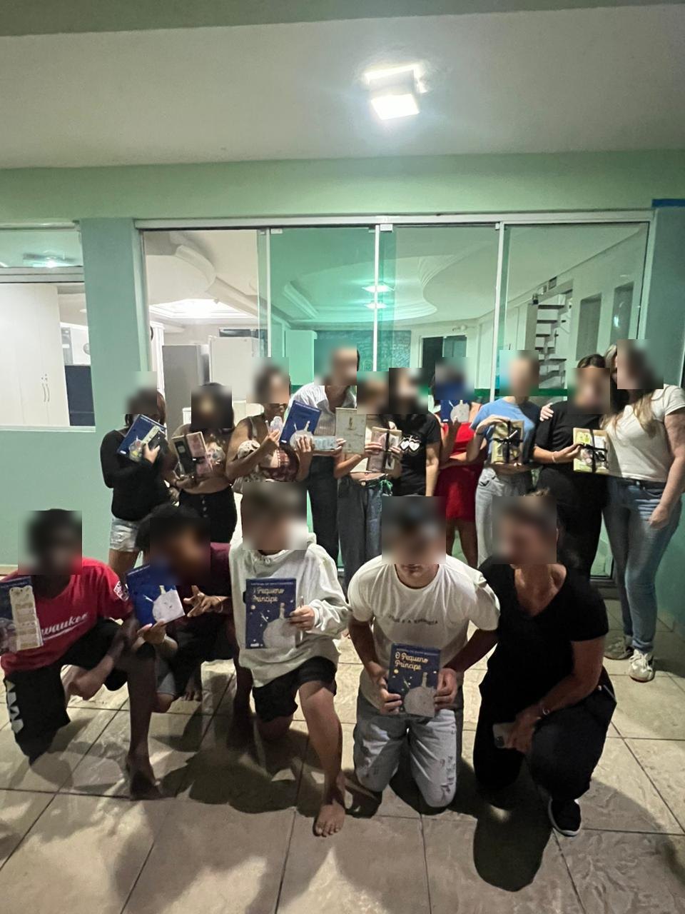 Grupo de adolescentes e voluntários exibe exemplares do livro O Pequeno Príncipe, com rostos desfocados para preservar a identidade