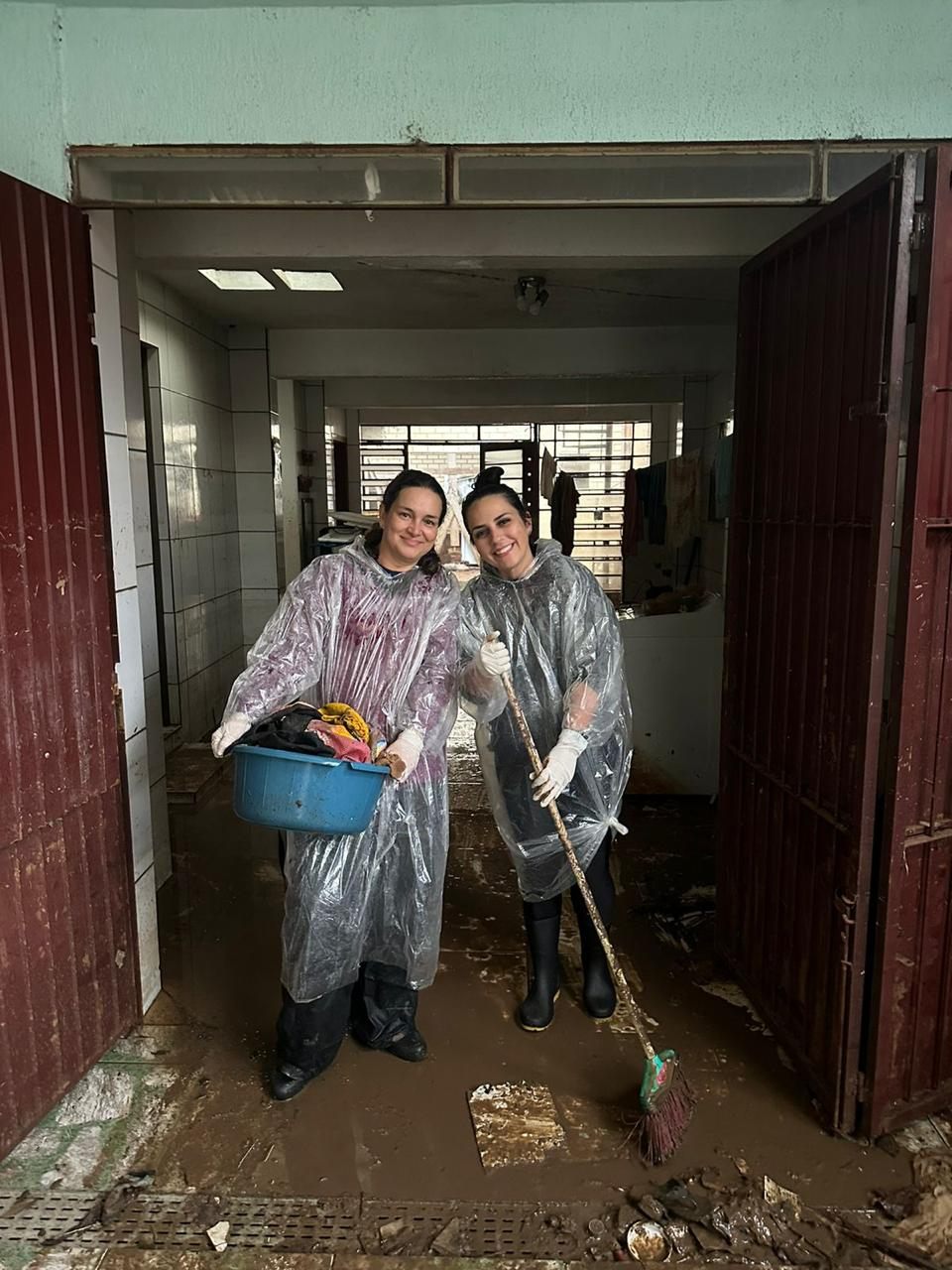 Voluntárias ajudam na limpeza de casa tomada pela lama após as enchentes